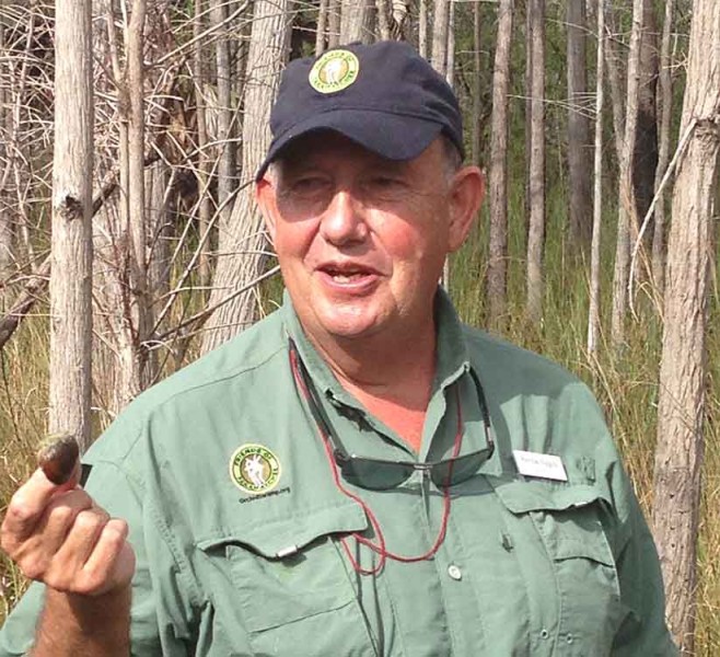 Patrick Higgins with an apple snail. Photo by Robert Fisher.